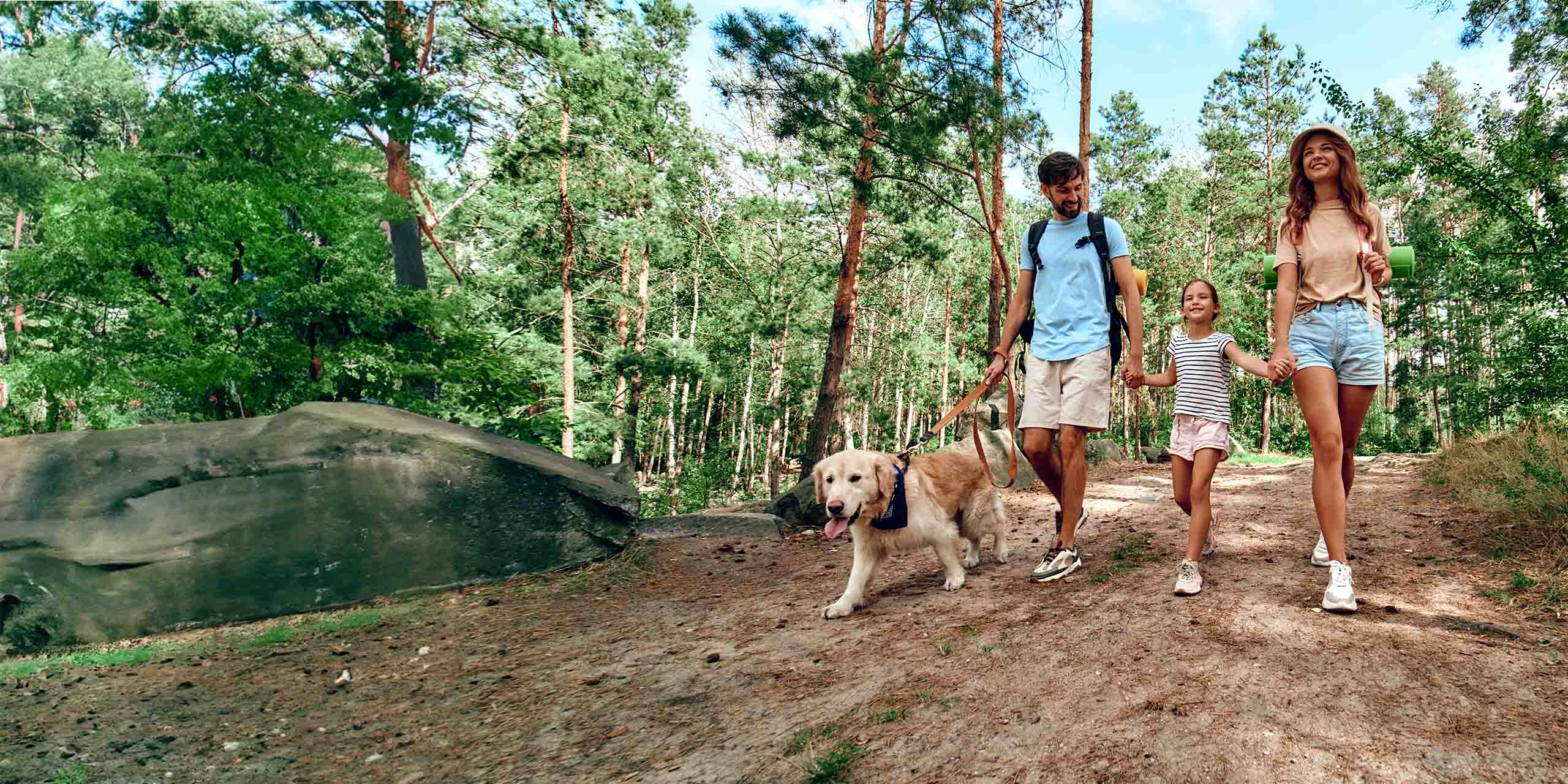Eine glückliche Familie läuft mit Hund durch den Wald. 